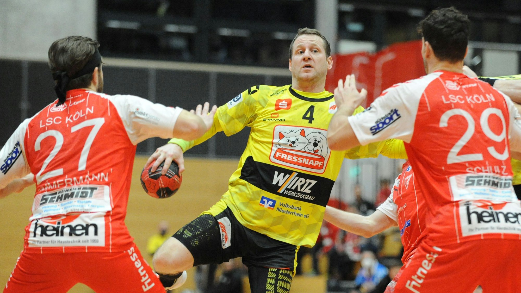 Merten Krings, Mitte, im Kampf gegen Max Zimmermann, links, und Lukas Martin Schulz, rechts, am Sonntag, den 05.12.2021, im Spiel HSG Krefeld Niederrhein gegen Longericher SC im Enni-Sportpark-Rheinkamp in Moers. HSG Krefeld Niederrhein, gelbe Trikots, spielt gegen Longericher SC, rote Trikots, in der 3. Handball-Bundesliga, Saison 2021/2022. Foto: Oleksandr Voskresenskyi / FUNKE Foto Services