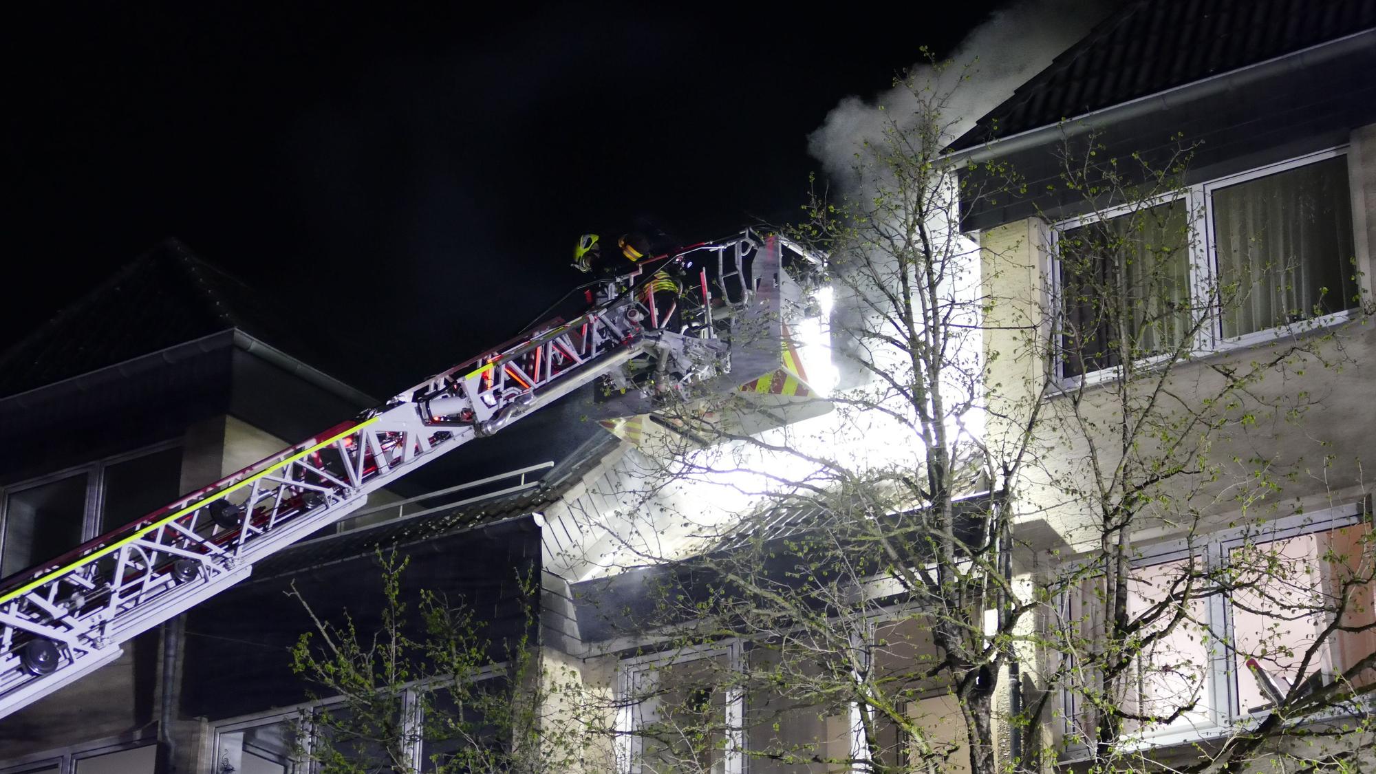 Ein Korb der Drehleiter vor einem Balkon, Qualm steigt auf.