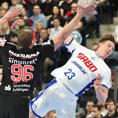 Ole Pregeler springt mit dem Ball in der Hand an Erlangens Tim Zechel vorbei.
