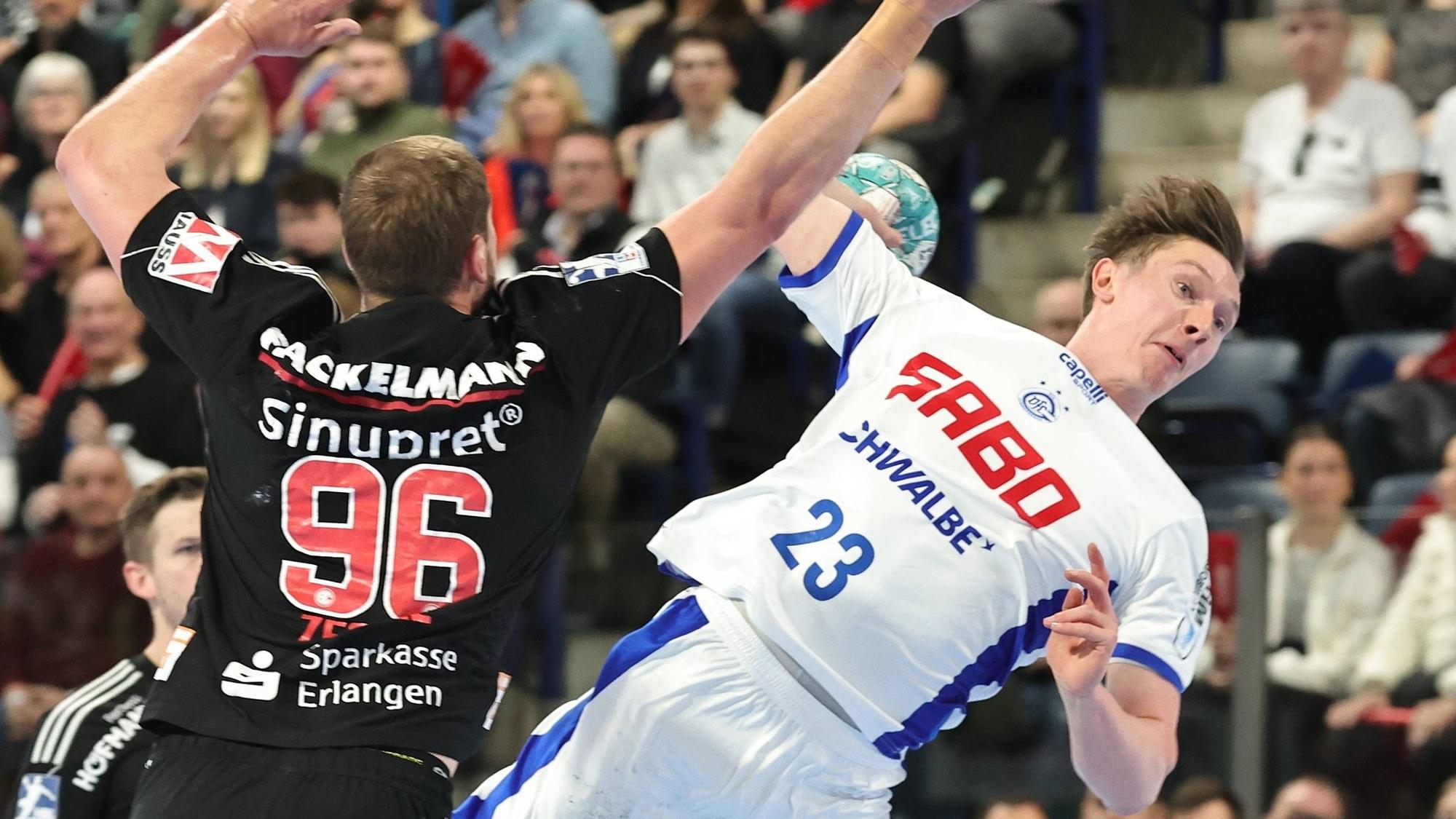 Ole Pregeler springt mit dem Ball in der Hand an Erlangens Tim Zechel vorbei.