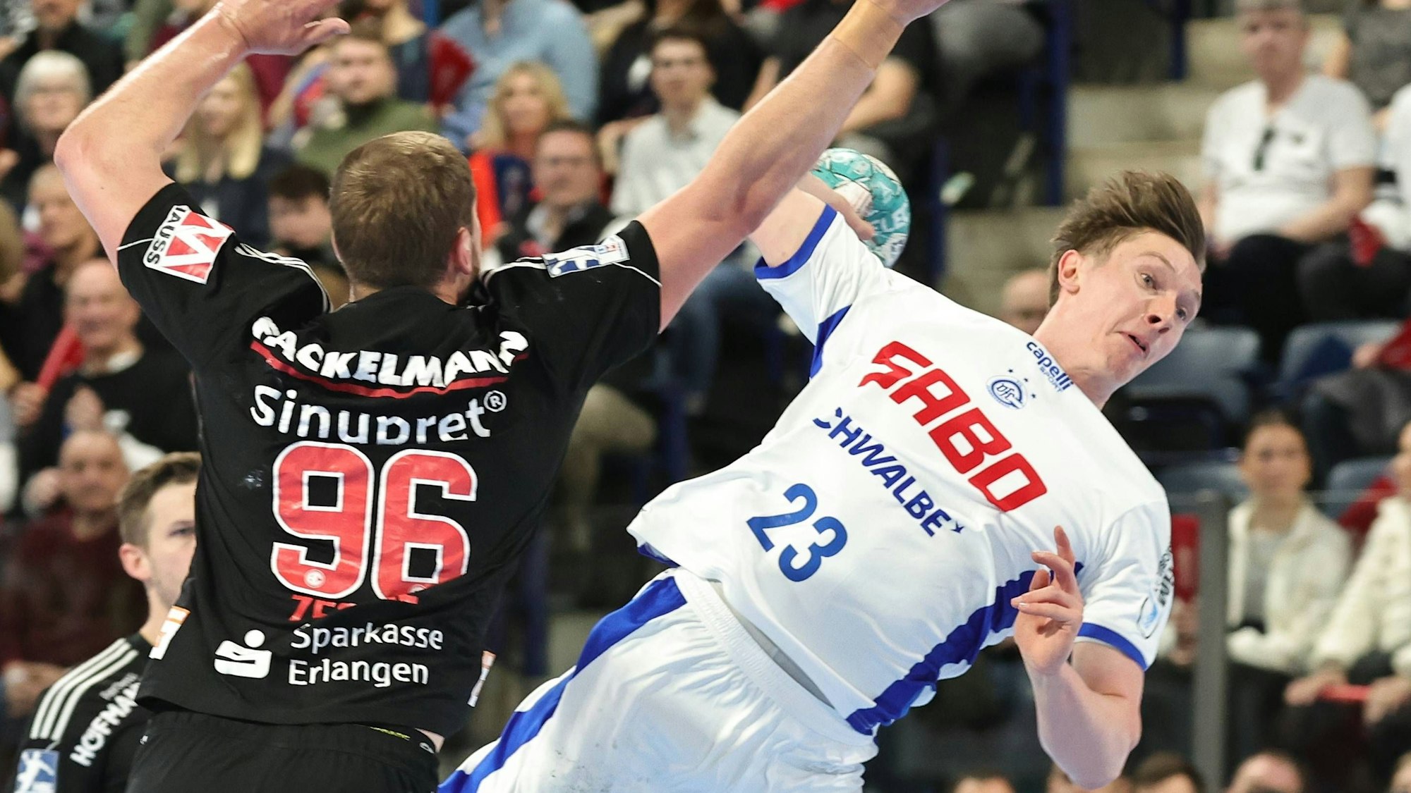 Ole Pregeler springt mit dem Ball in der Hand an Erlangens Tim Zechel vorbei.