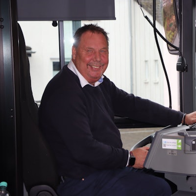 Zu sehen ist ein Mann am Steuer eines Busses.