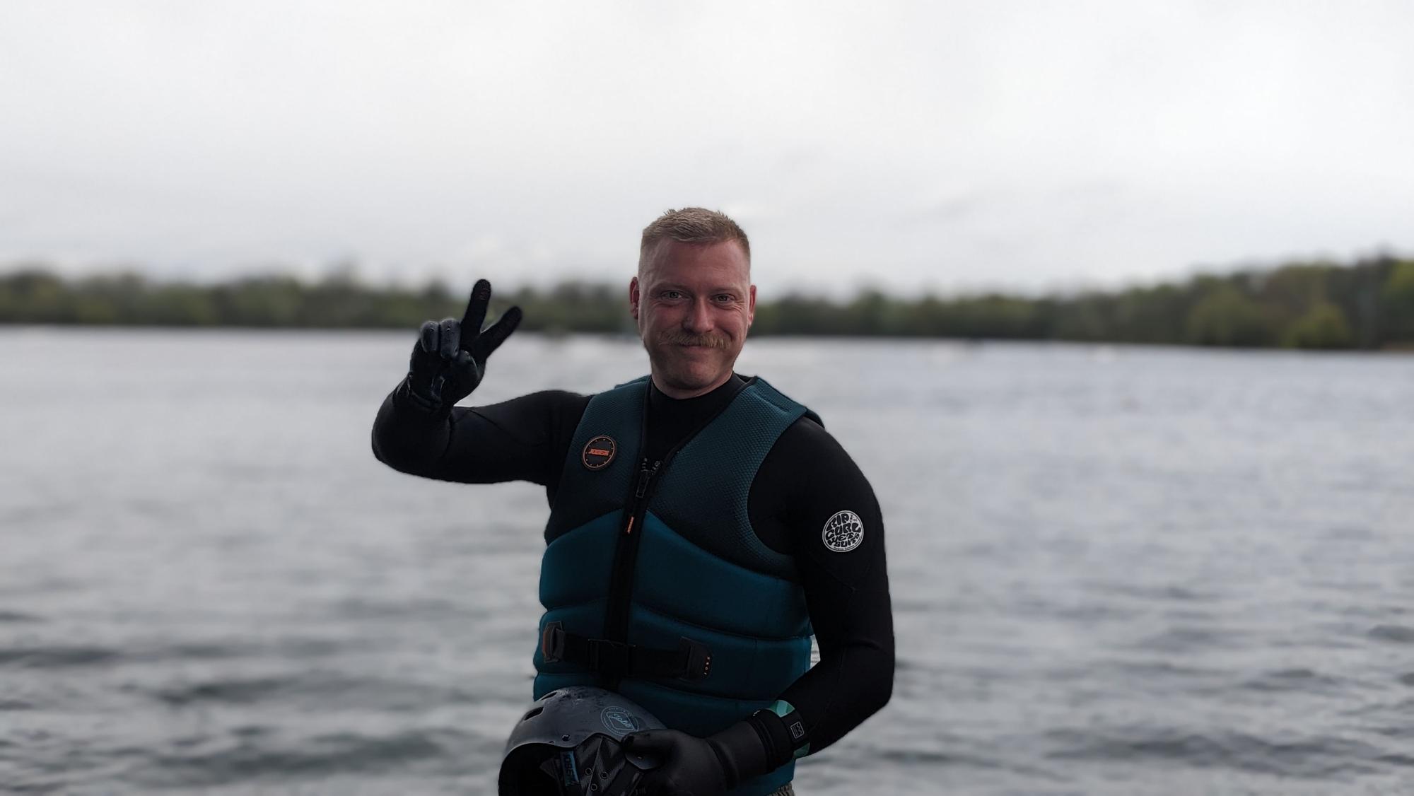 Daniel Teybig steht in Wasserweste vor dem Rather See.