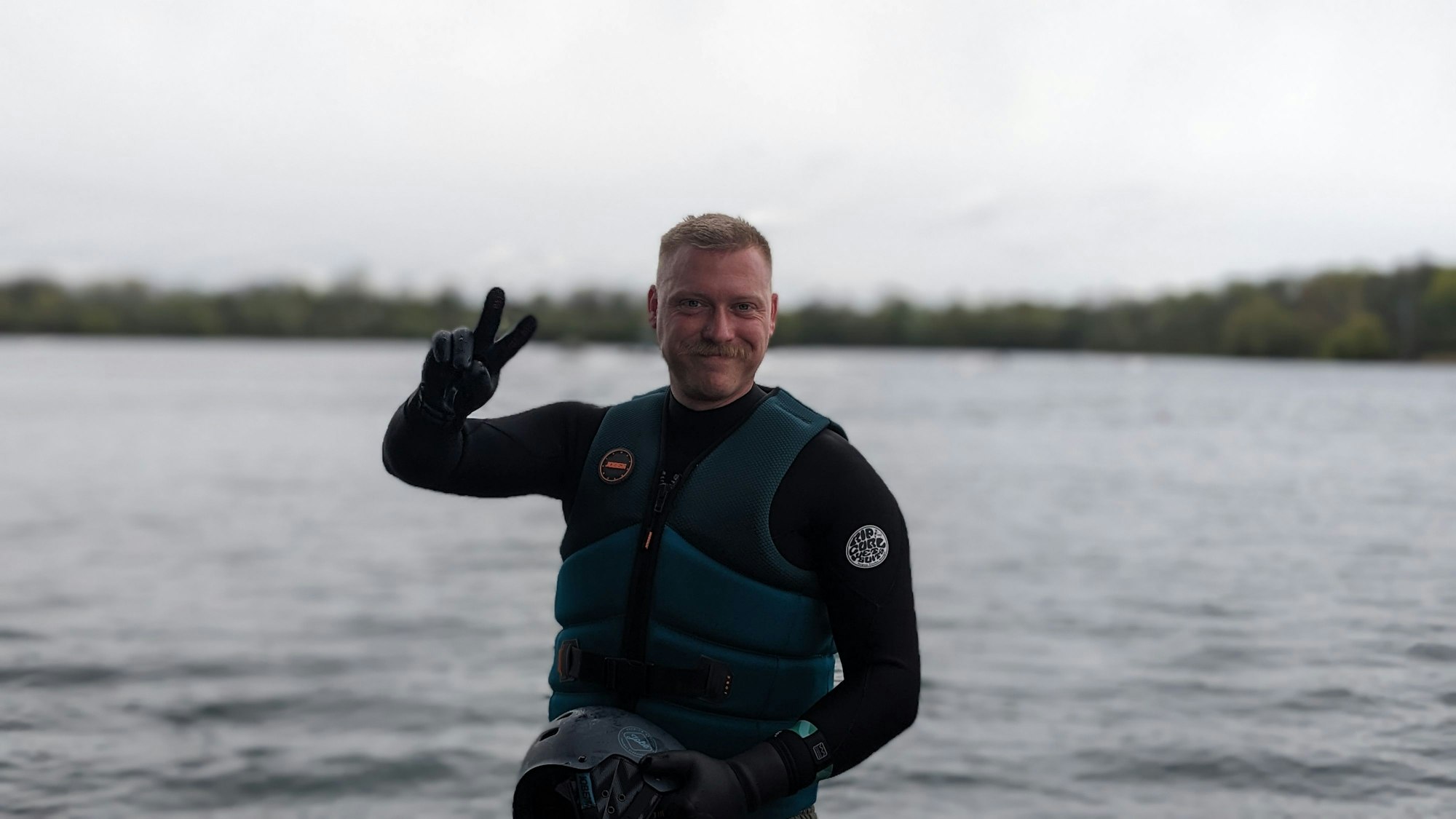 Daniel Teybig steht in Wasserweste vor dem Rather See.