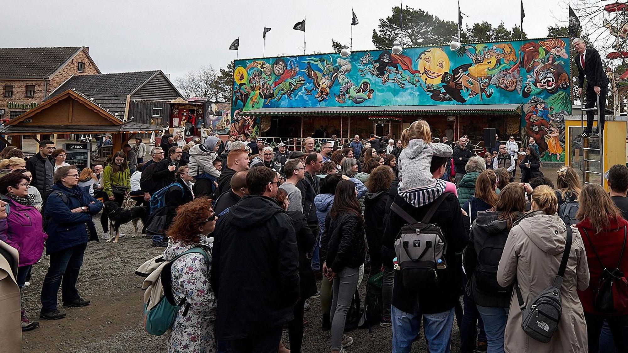 Zahlreiche Besucher stehen in Kommern beim Jahrmarkt anno dazumal vor einer Kimesbude. Rechts hinten ist ein Schausteller auf einer Leiter zu sehen.
