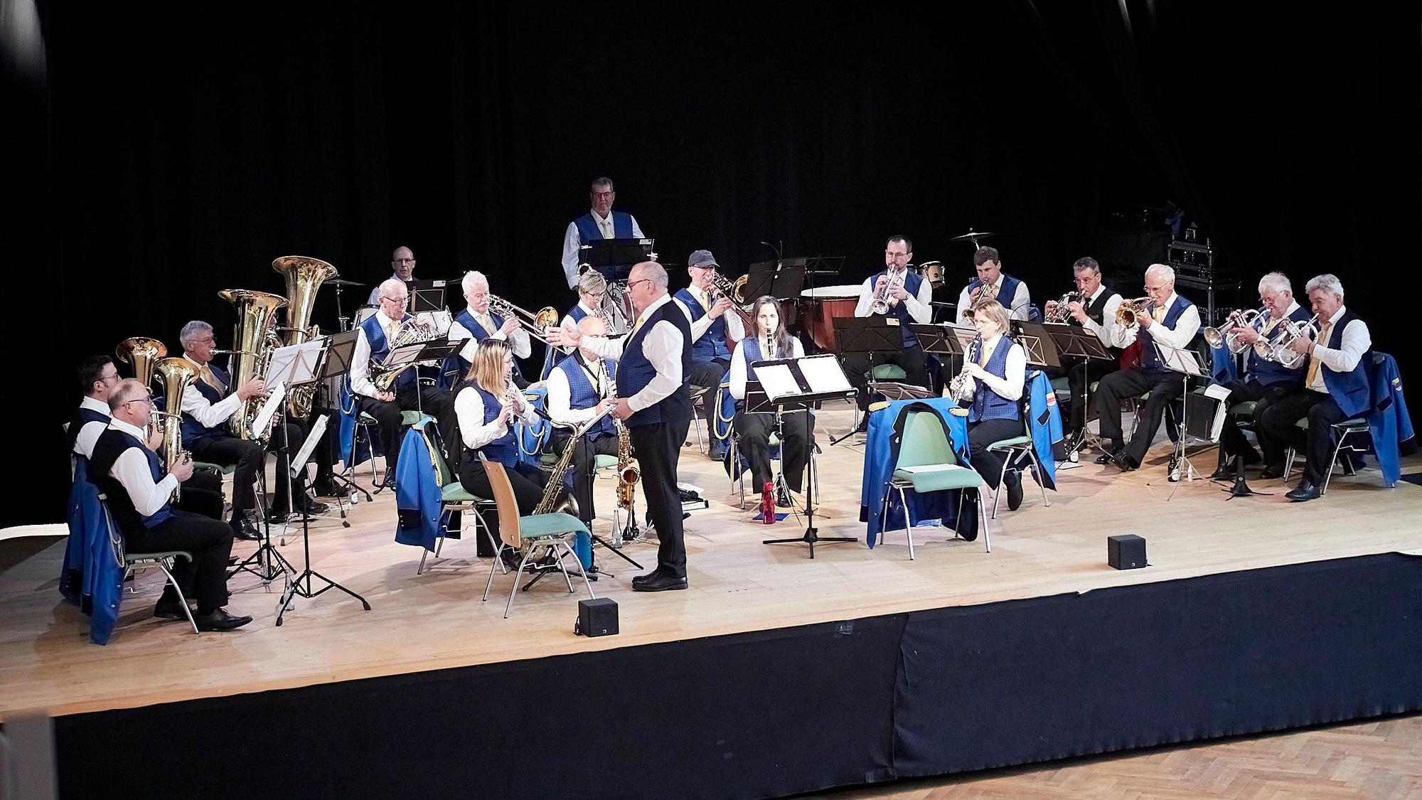 Die rund 25 Mitglieder des Orchesters präsentierten sich in blauen Westen. Der Dirigent schaut in Richtung der Bläser, um ihnen ihren Einsatz anzuzeigen.