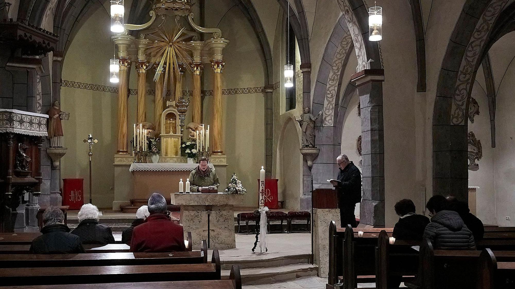 Ein Mann steht am Altar, in denen Reihen sind rund 10 Besucher von hinten zu sehen.