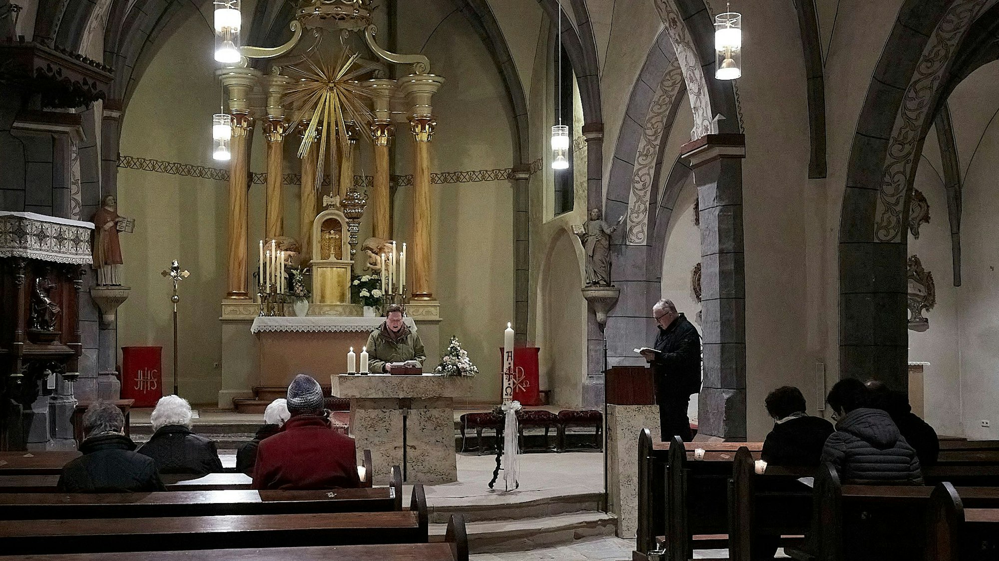 Ein Mann steht am Altar, in denen Reihen sind rund 10 Besucher von hinten zu sehen.
