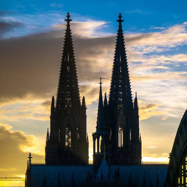 Die Sonne geht hinter dem Kölner Dom und der Hohenzollernbrücke unter, mehrere Wolken schieben sich vor den blauen Himmel. (Symbolbild)