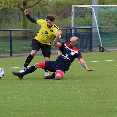 Ein Fußballer stoppt einen Flankenlauf mithilfe eine Grätsche.