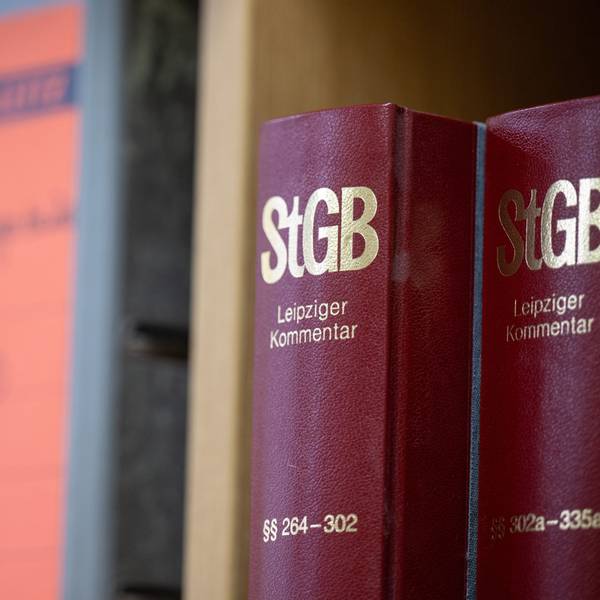 Bücher mit StGB-Gesetzeskommentaren stehen neben Aktenordnern.