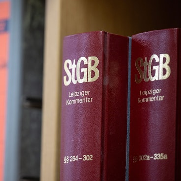 Bücher mit StGB-Gesetzeskommentaren stehen neben Aktenordnern.