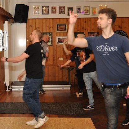 Darts-Spieler werfen ihre Pfeile auf Scheiben, die an der mit Holz verkleideten Wand hängen.