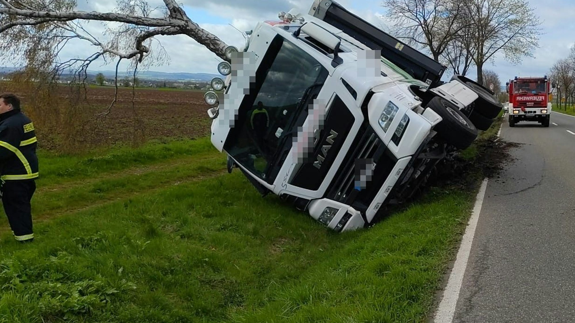 Das Bild zeigt den Sattelschlepper, wie er in den Graben gestürzt ist und das Führerhaus einen Baum entwurzelt hat.