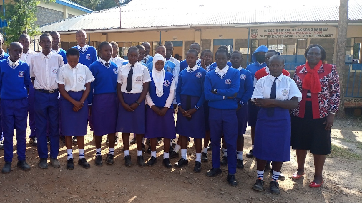 Das Foto zeigt eine Gruppe von Schülerinnen und Schülern in Schuluniform vor der Kabarnet-Hürth-Schule in der Partnerstadt in Kenia.