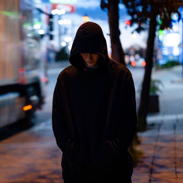 Faceless man with a black hoodie in the night city