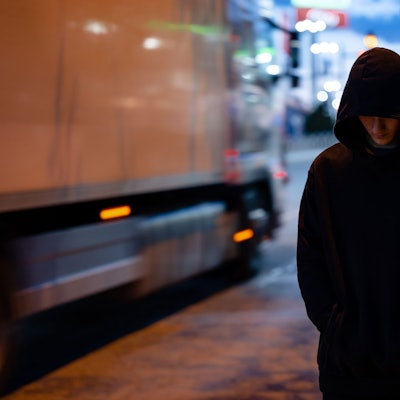 Faceless man with a black hoodie in the night city