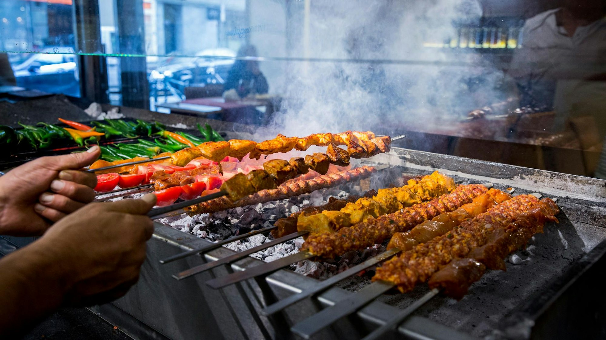 Auf einem Holzkohlegrill werden Fleischspieße gegart.
