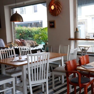 Das Café Bo in Zollstock von innen, zwei Holztische mit Holzstühlen und große Fenster