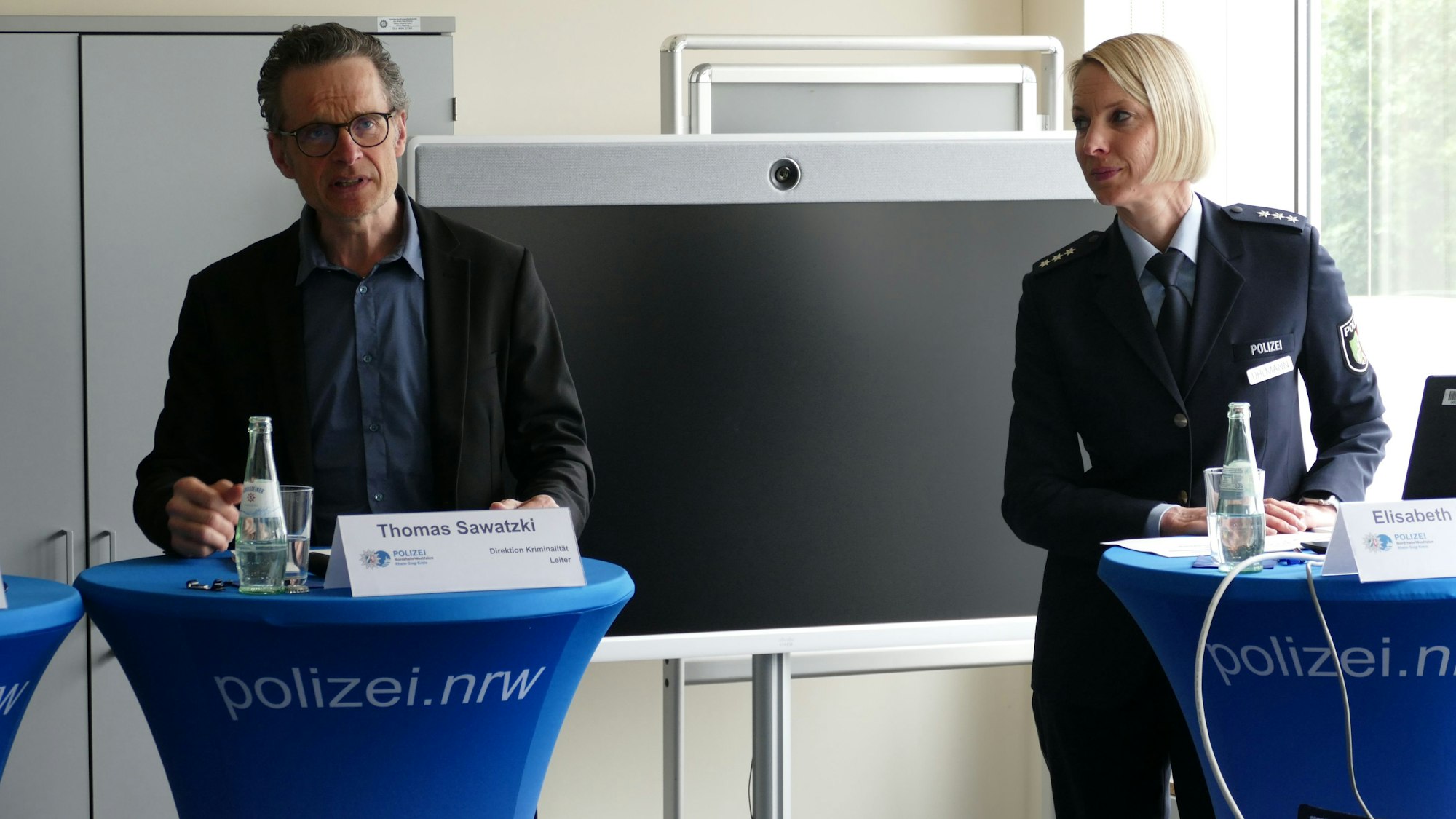 Eine Frau und ein Mann stehen an Stehtischen.