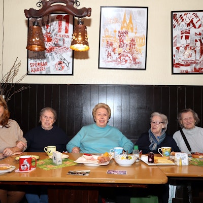 Sechs Seniorinnen, die an einem Tisch mit Frühstücksgedeck in einer Kölner Kneipe sitzen