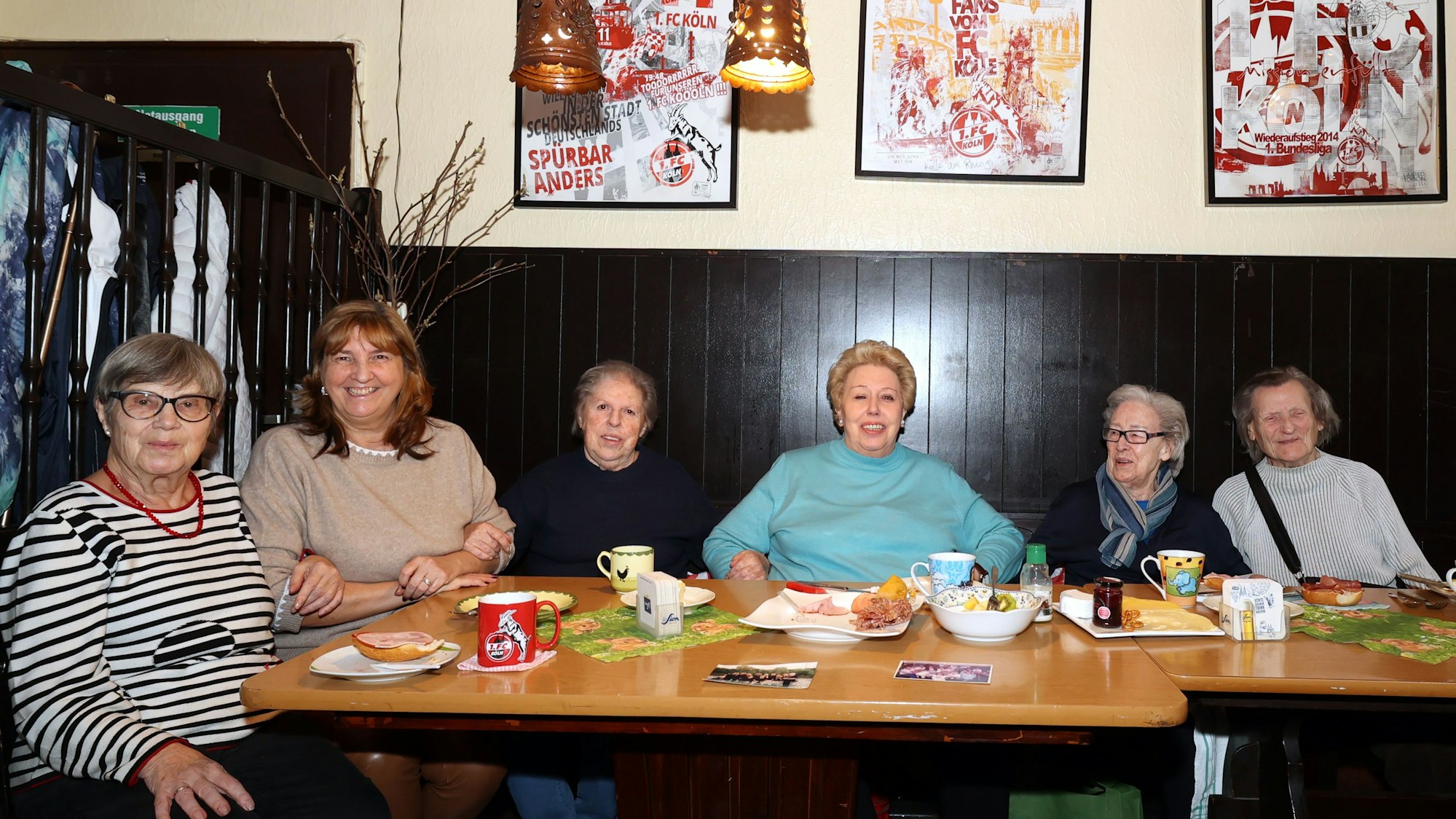 Sechs Seniorinnen, die an einem Tisch mit Frühstücksgedeck in einer Kölner Kneipe sitzen