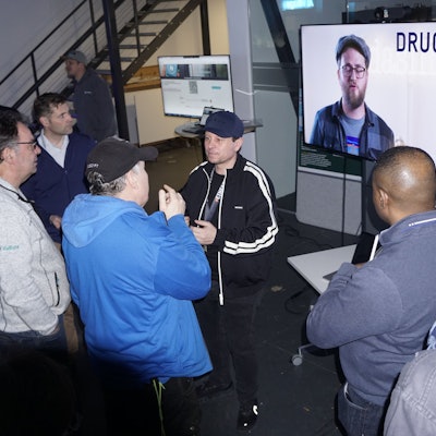 Vertreter von Handwerksbetrieben stehen vor einem großen Bildschirm im AI Village und diskutieren mit einem Experten.