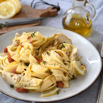 Neben der cremigen Artischockensoße machen auch gegrillte Artischockenherzen, knuspriger Bauchspeck und süßliche Zitrusnoten aus einfachen Bandnudeln einen herzhaften Pastaschmaus.