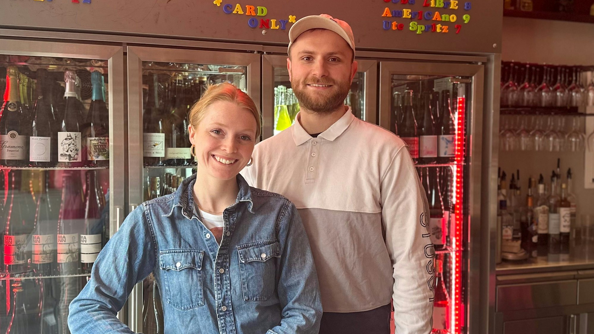 Ein junger Mann und eine junge Frau stehen hinter einer Bar und lächeln