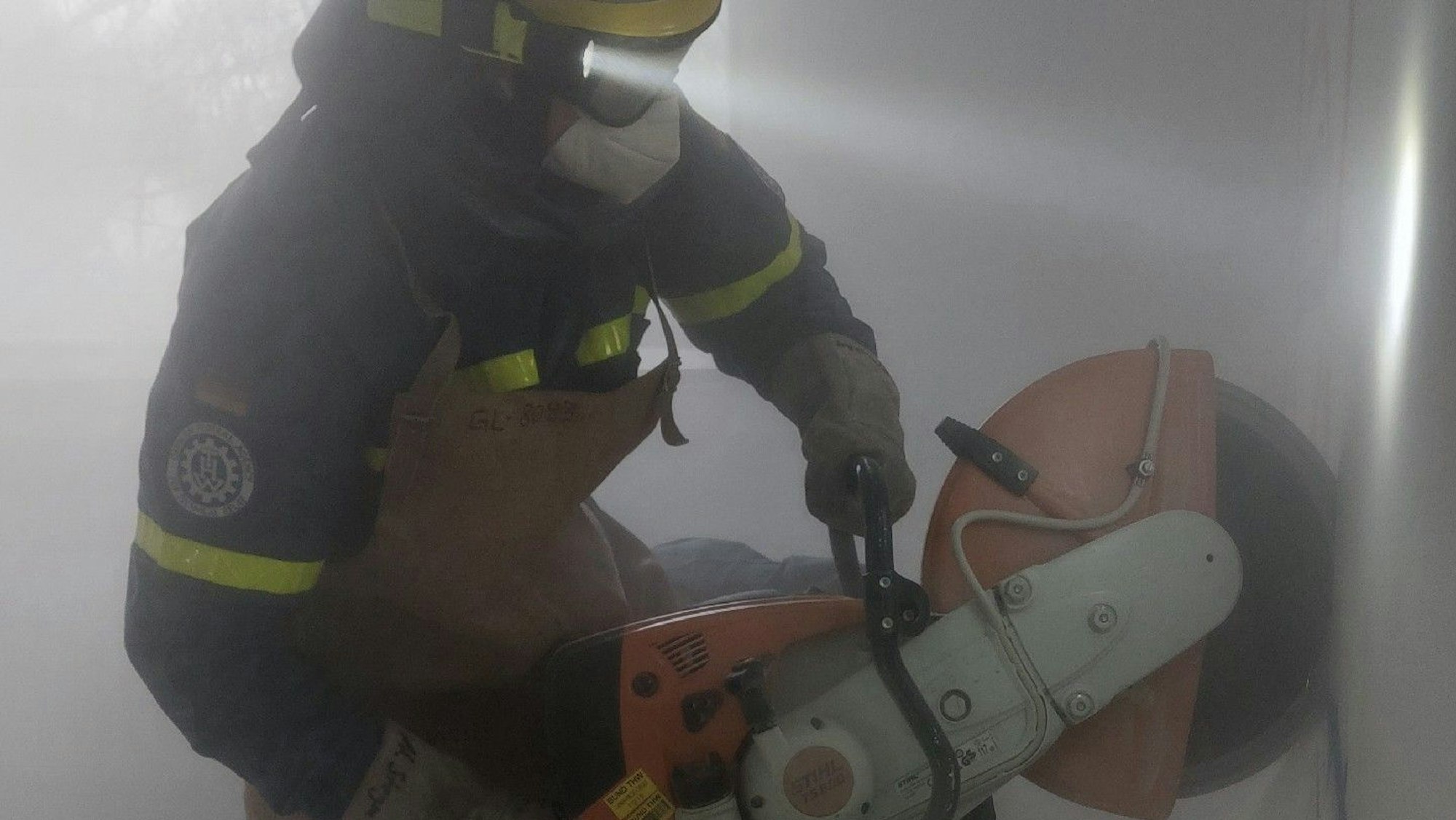 Ein THW-Helfer schneidet mit schwerem Gerät ein Loch in eine Wand.