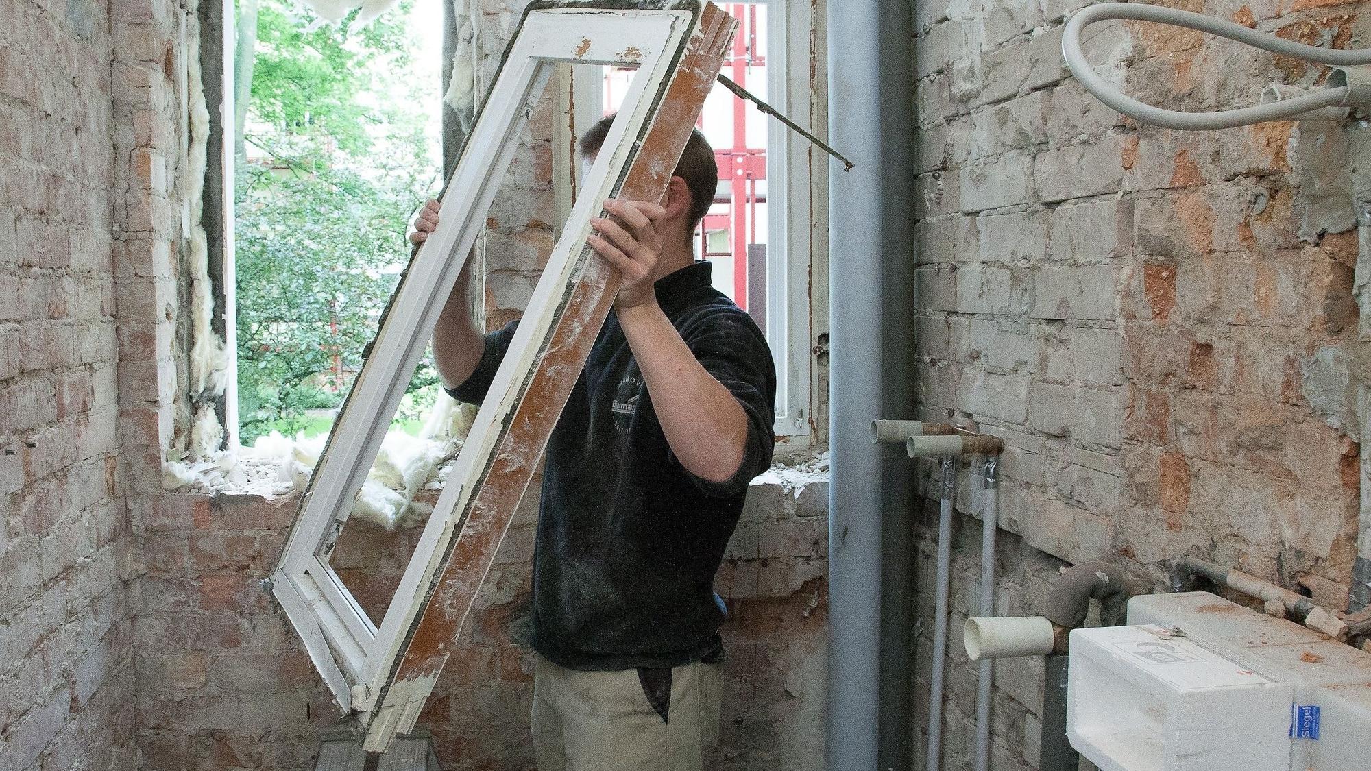 Ein Mann baut ein Fenster aus einem alten Haus aus.