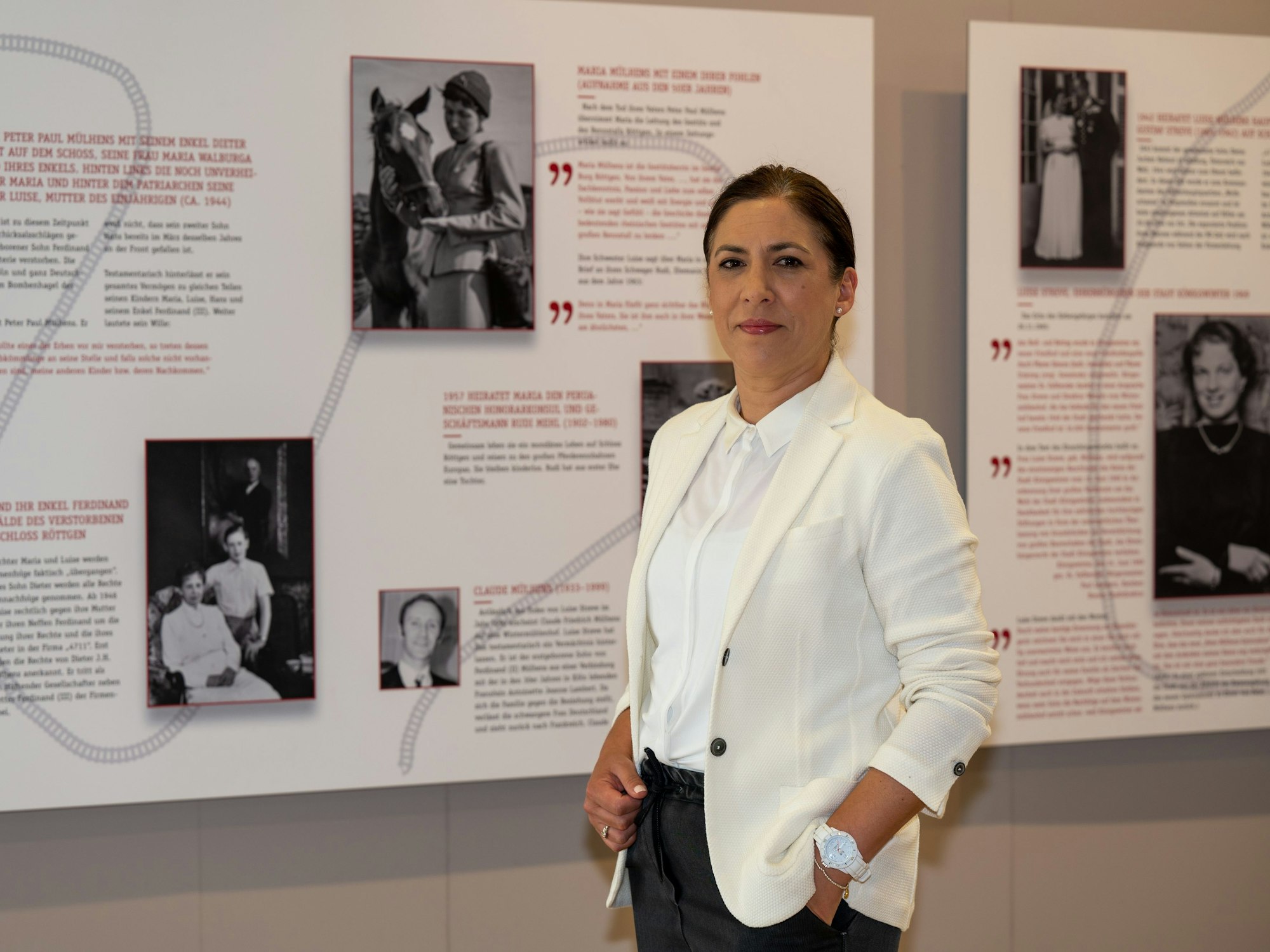 Fiona Streve-Mülhens Achenbach vor einer Tafel mit Bildern von Menschen und Pferden.