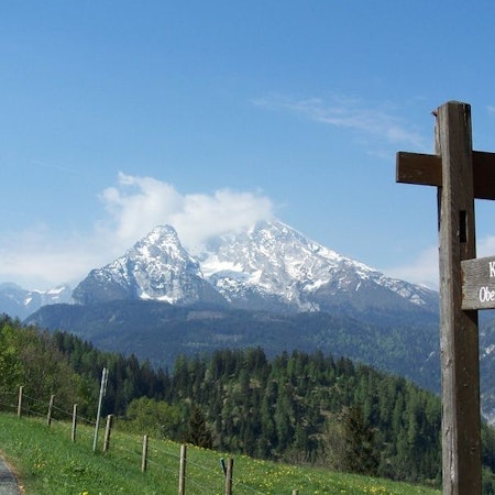 Ein Wegweiser steht vor den Berchtesgadener Alpen.
