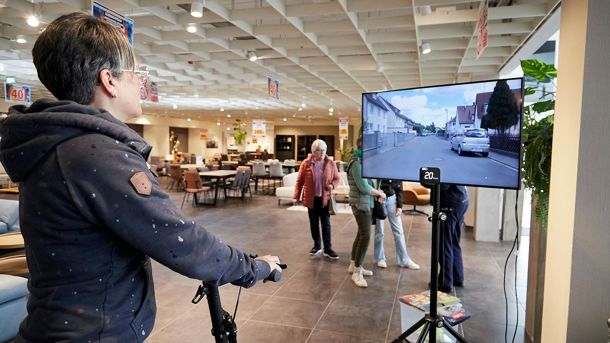Monika Leyendecker fährt mit einem E-Scooter-Simulator. Ihre Strecke sieht sie auf einem Bildschirm.