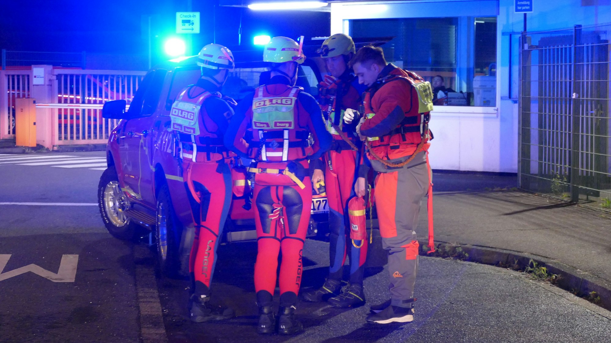 Menschen in Neoprenanzügen stehen an einem Fahrzeug.
