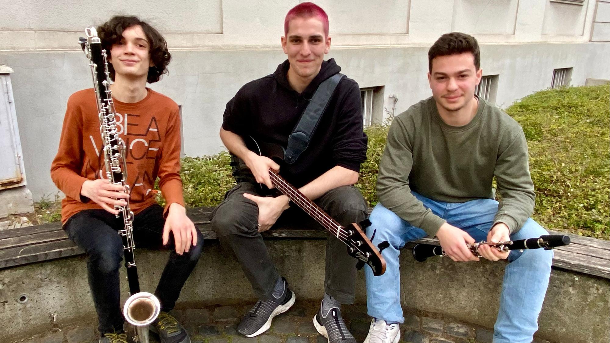 Zu sehen sind drei junge Musiker mit ihren Instrumenten.