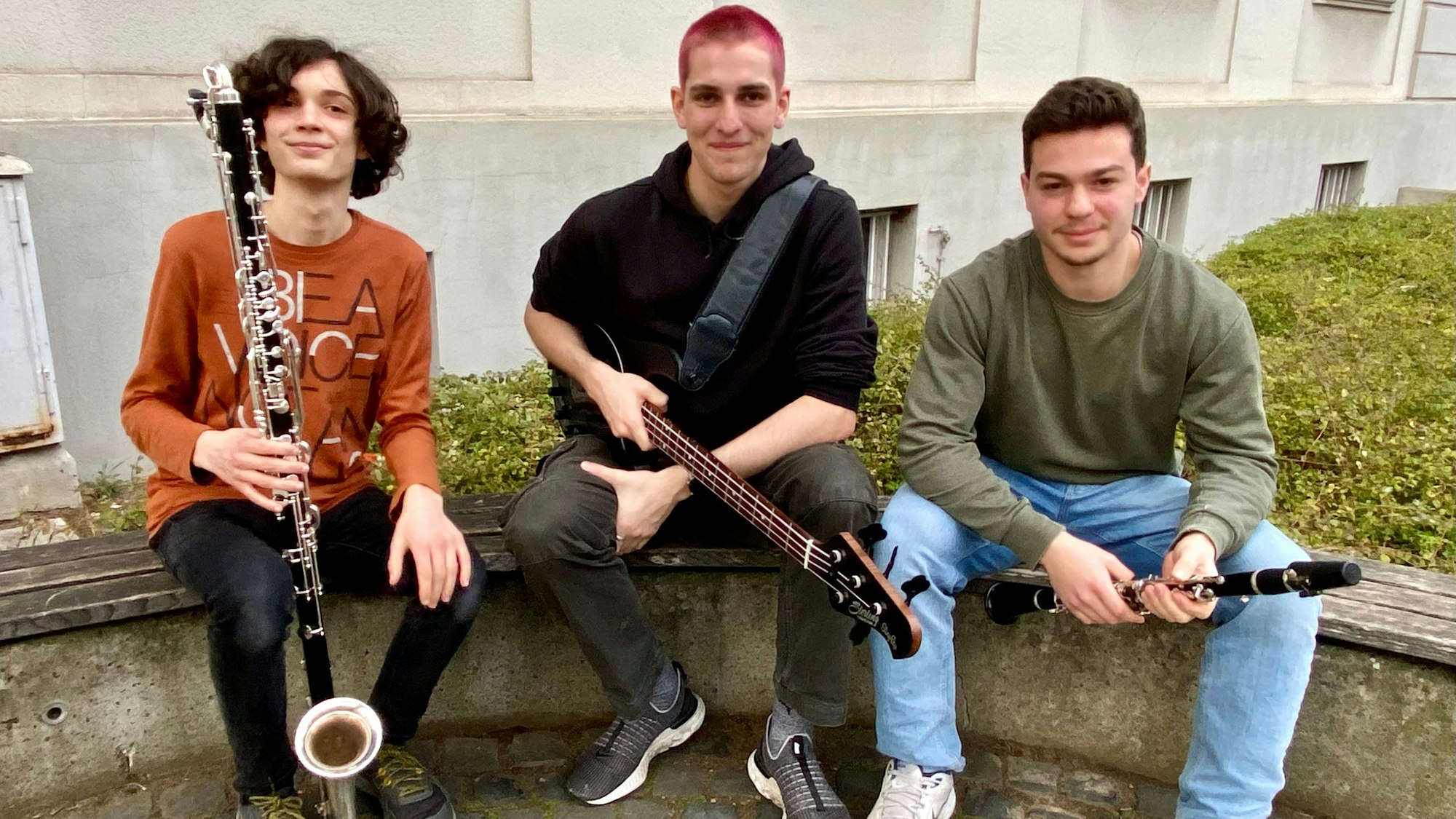 Zu sehen sind drei junge Musiker mit ihren Instrumenten.