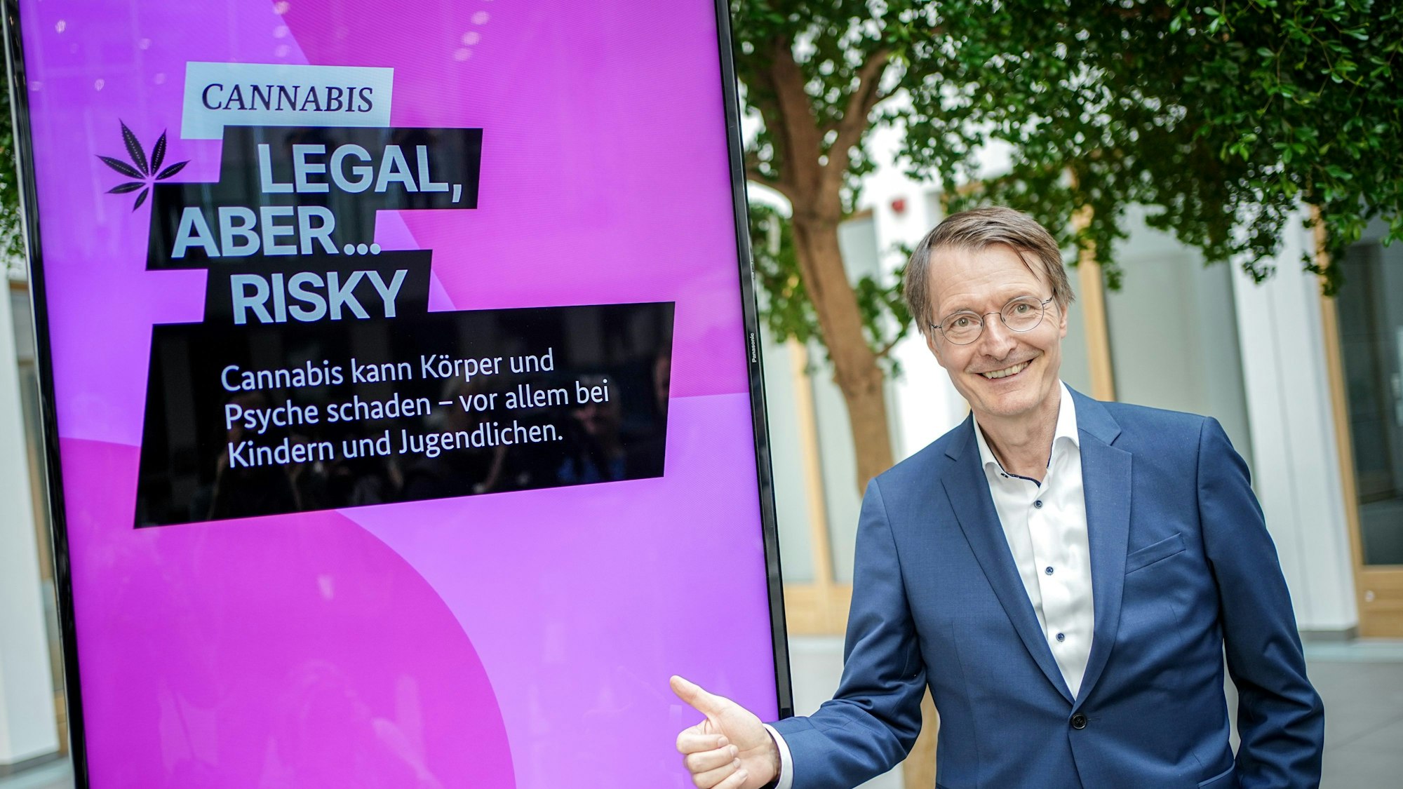 Bundesgesundheitsminister Karl Lauterbach (SPD) steht im Sommer 2023 vor dem Plakat einer Aufklärungskampagne zu den Gefahren von Cannabis. Das Plakat warnt: „Cannabis – Legal, aber risky. Cannabis kann Körper und Psyche schaden – vor allem bei Kindern und Jugendlichen“.