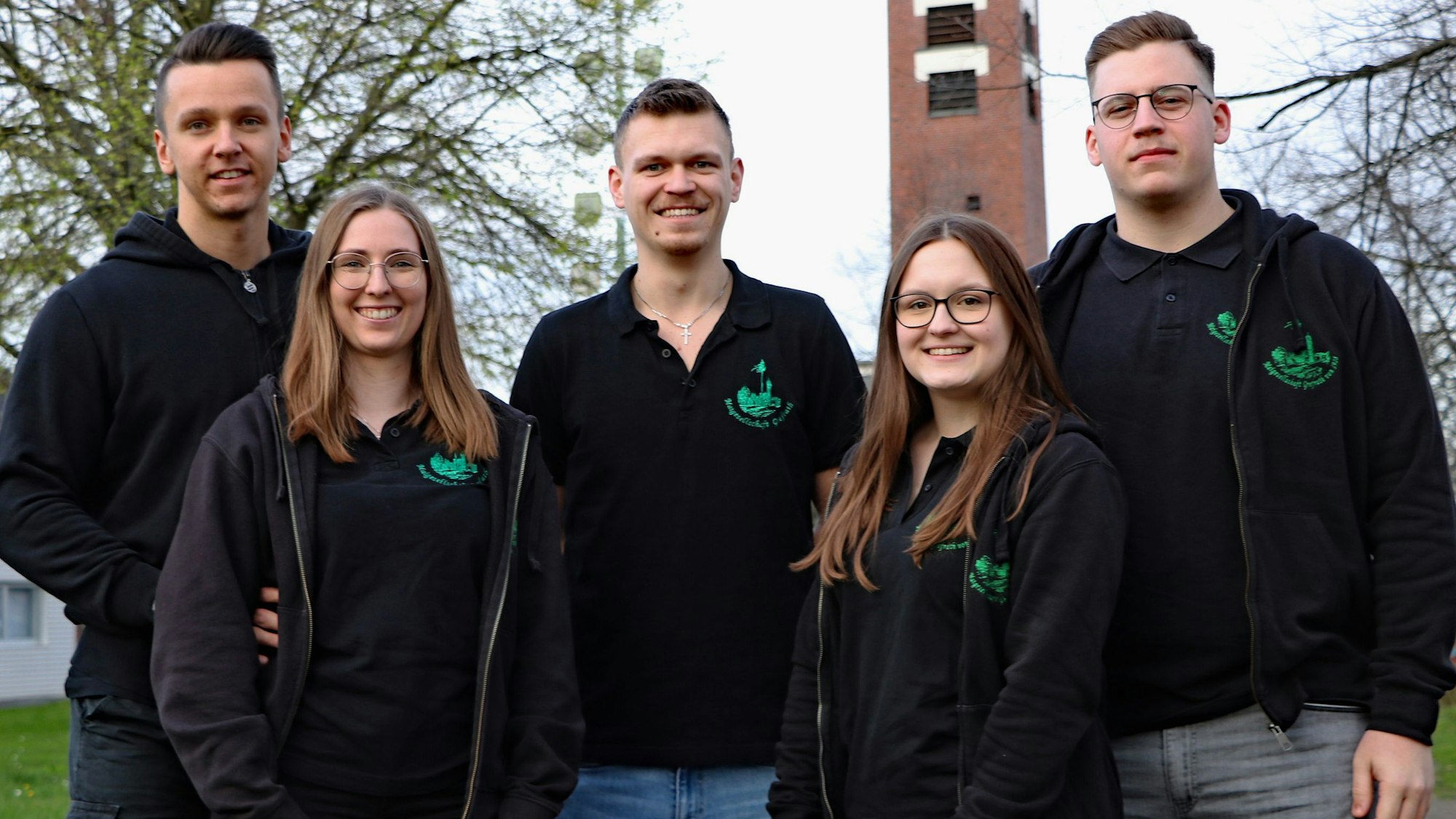 Zwei Frauen und drei Männer lächeln in die Kamera.