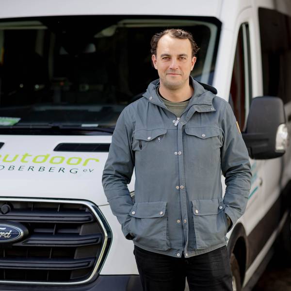 Ein junger Mann steht vor einem Transporter.