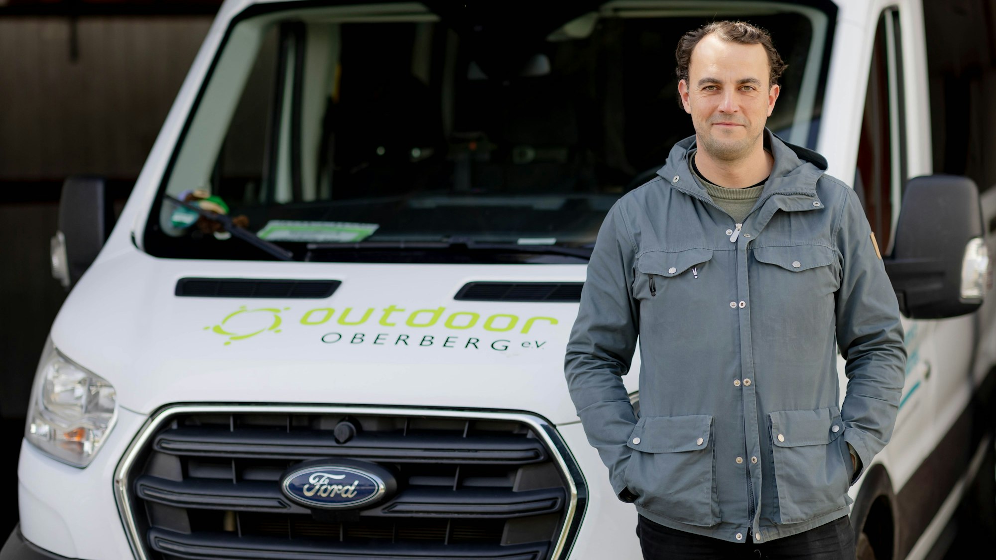 Ein junger Mann steht vor einem Transporter.