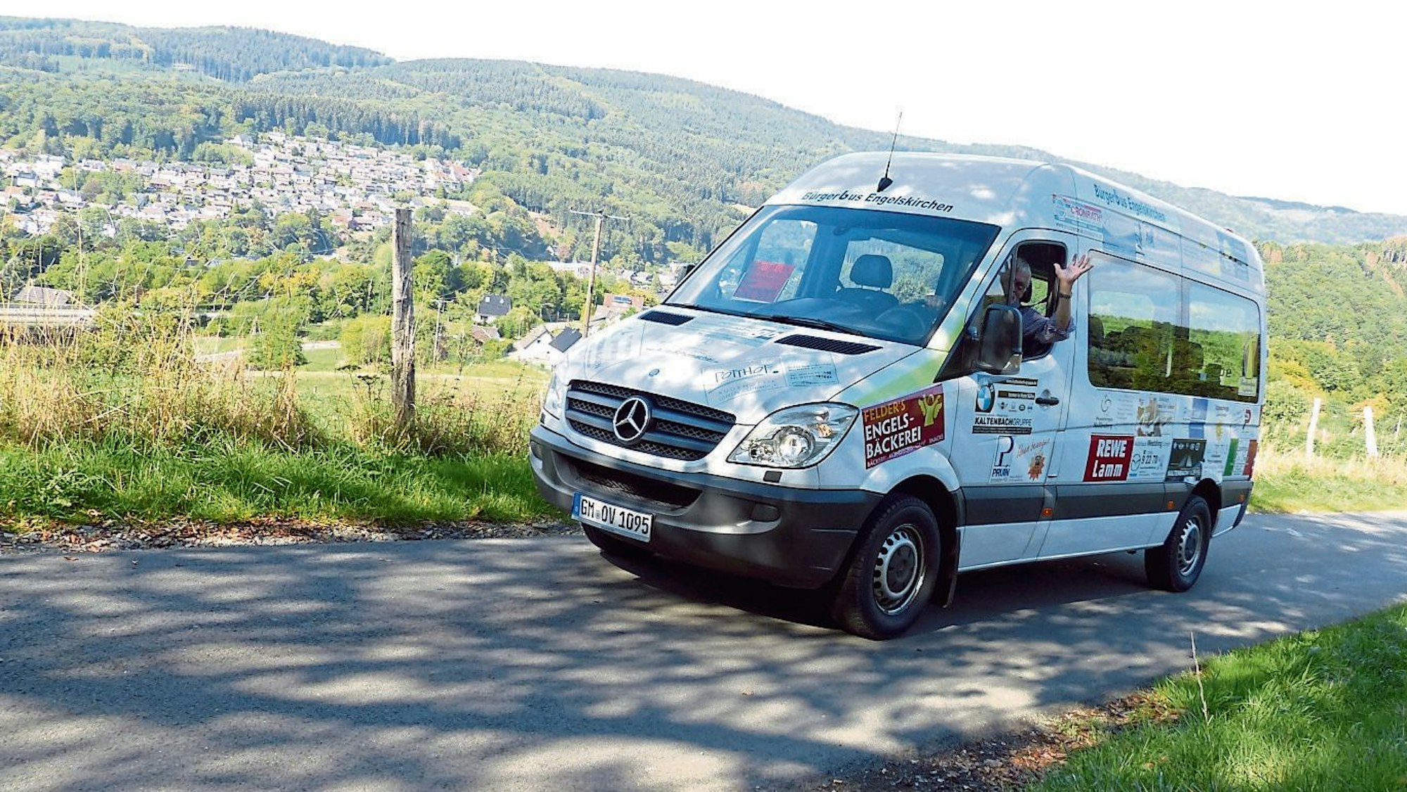 Der Bürgerbus Engelskirchen unterwegs. Der Fahrer winkt.