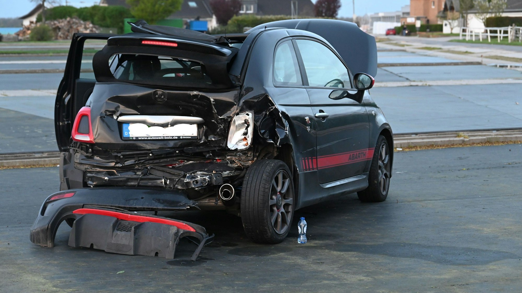 Ein am Heck stark beschädigtes Auto steht auf einer flachen Fläche.