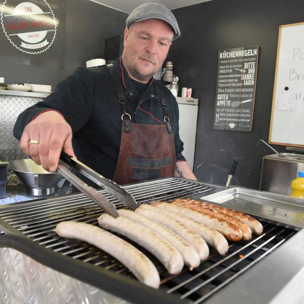 Der gelernte Metzger legt Würste auf den Grill.