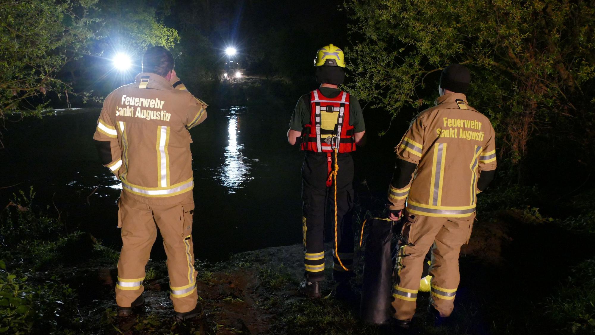 Feuerwehrleute stehen in Meindorf am Siegufer.