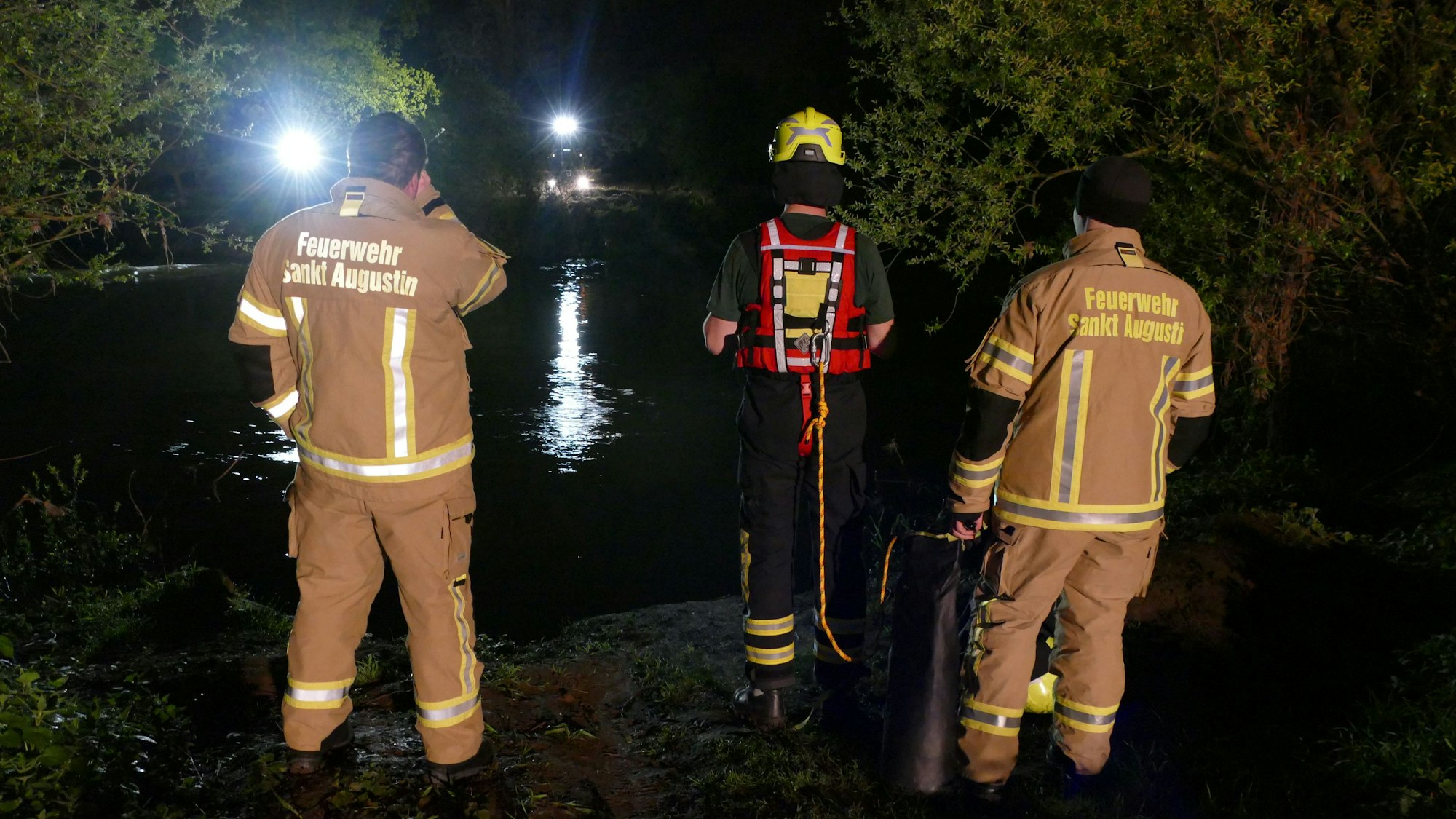 Feuerwehrleute stehen in Meindorf am Siegufer.