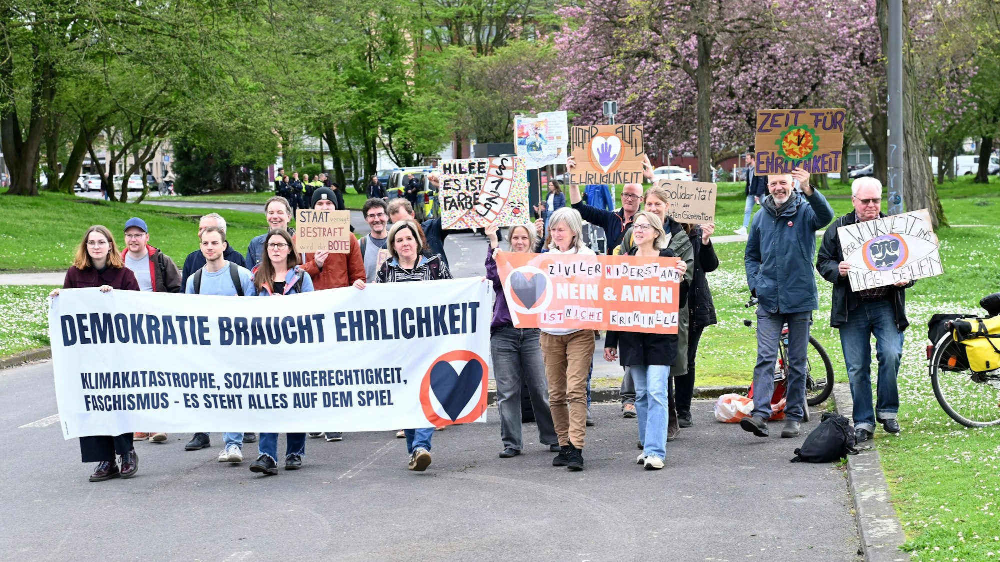 Unterstützer der „Letzten Generation“ laufen eine Straße entlang und halten Plakate hoch.