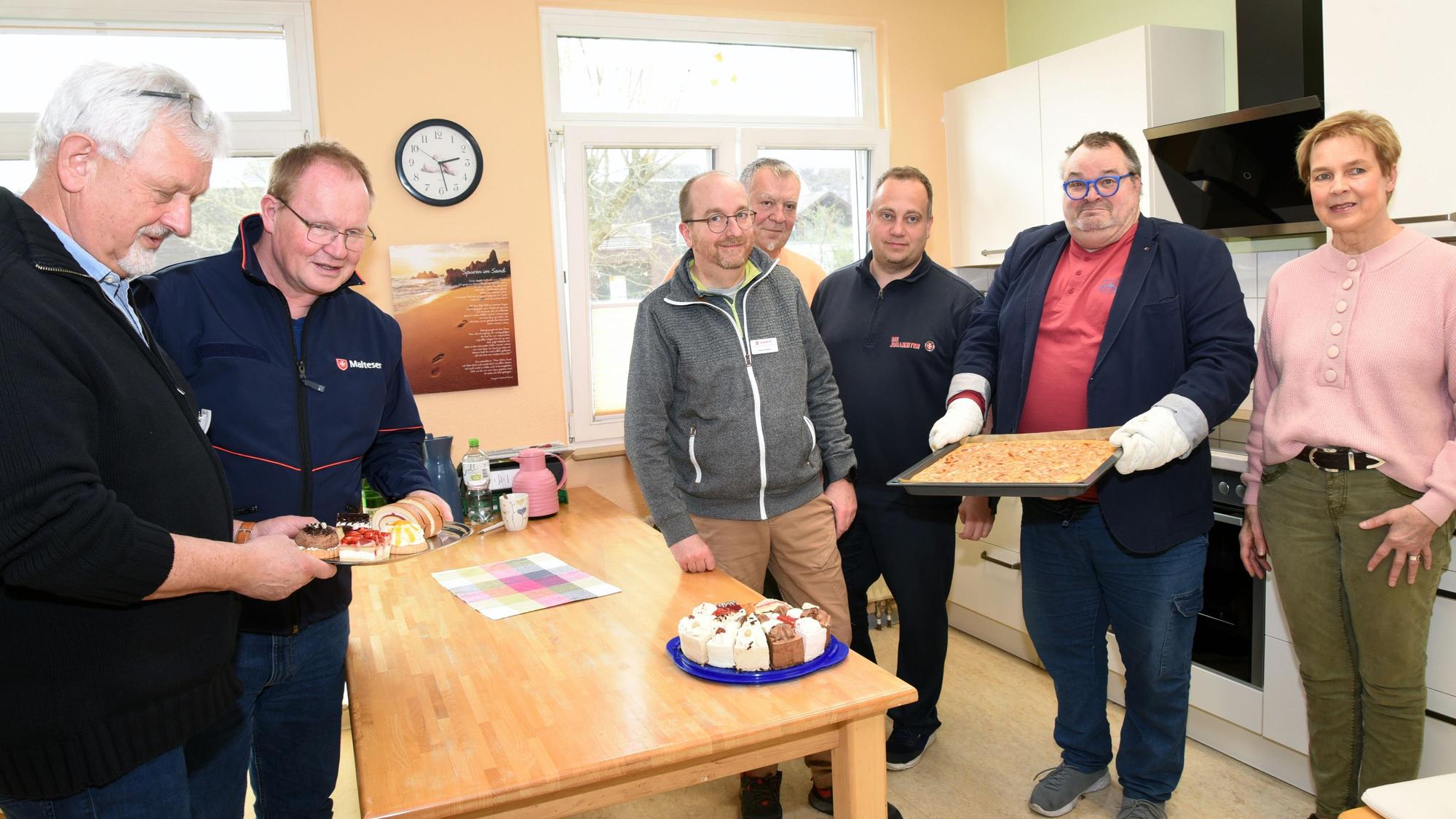 Eine Gruppe steht in einer Küche und hantiert mit Kuchen.