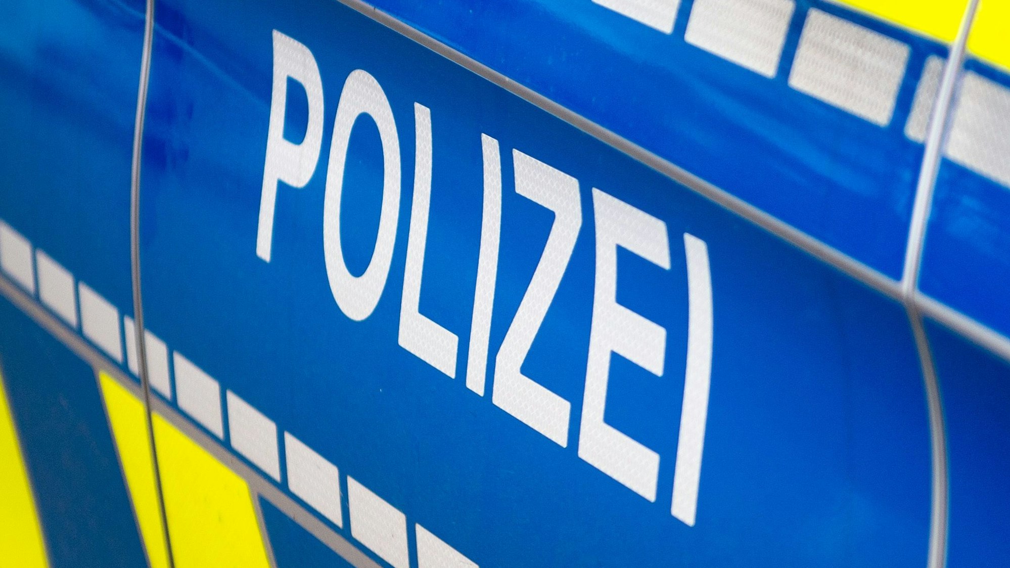 Das Symbolbild zeigt die Tür eines Polizeiautos.