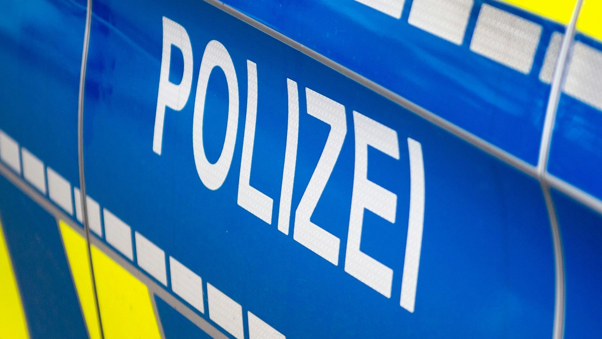 Auf einem blauen Polizeiauto steht das Wort: Polizei.